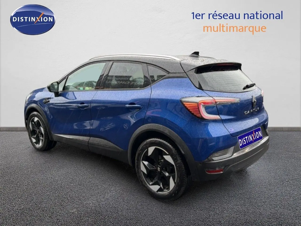 Vue 3/4 arrière droite du Renault Captur 2025 bleu Iron Metal avec toit noir et jantes stylisées bicolores.