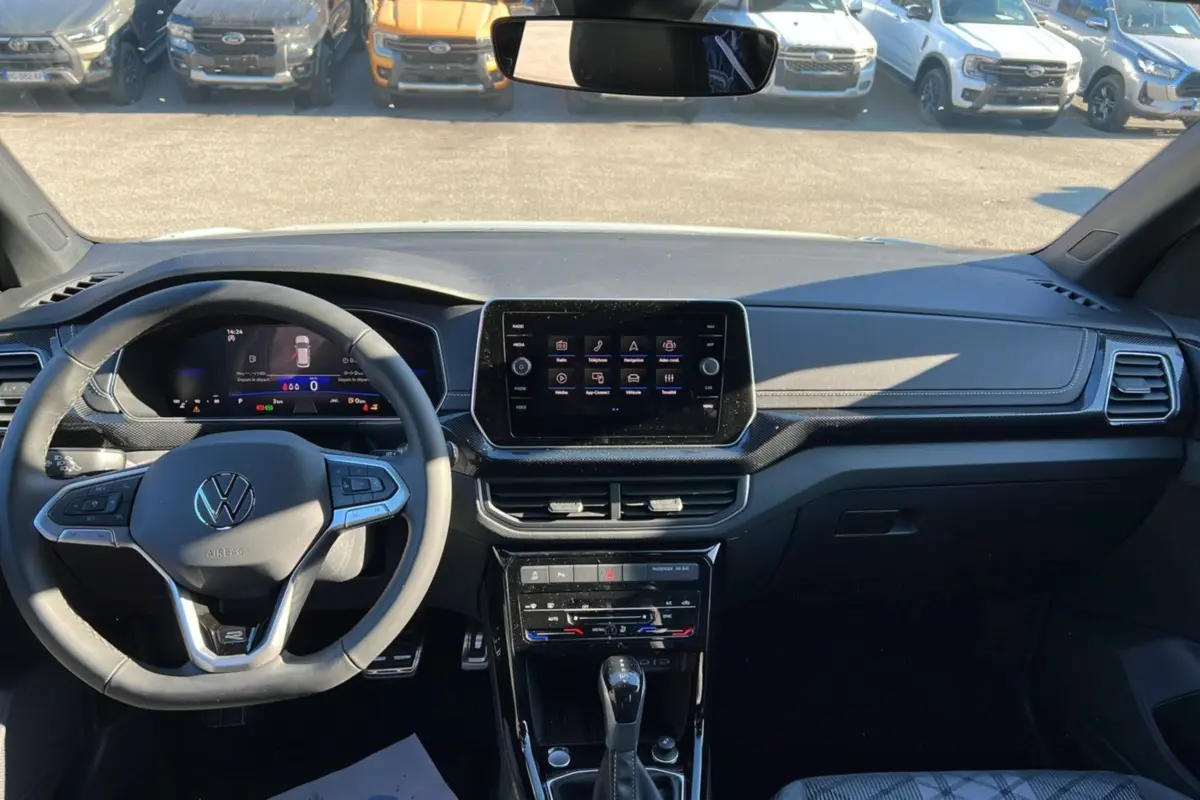 Vue intérieure avant du Volkswagen T-Cross blanc pur 2025, tableau de bord avec écran tactile et volant multifonctions cuir.