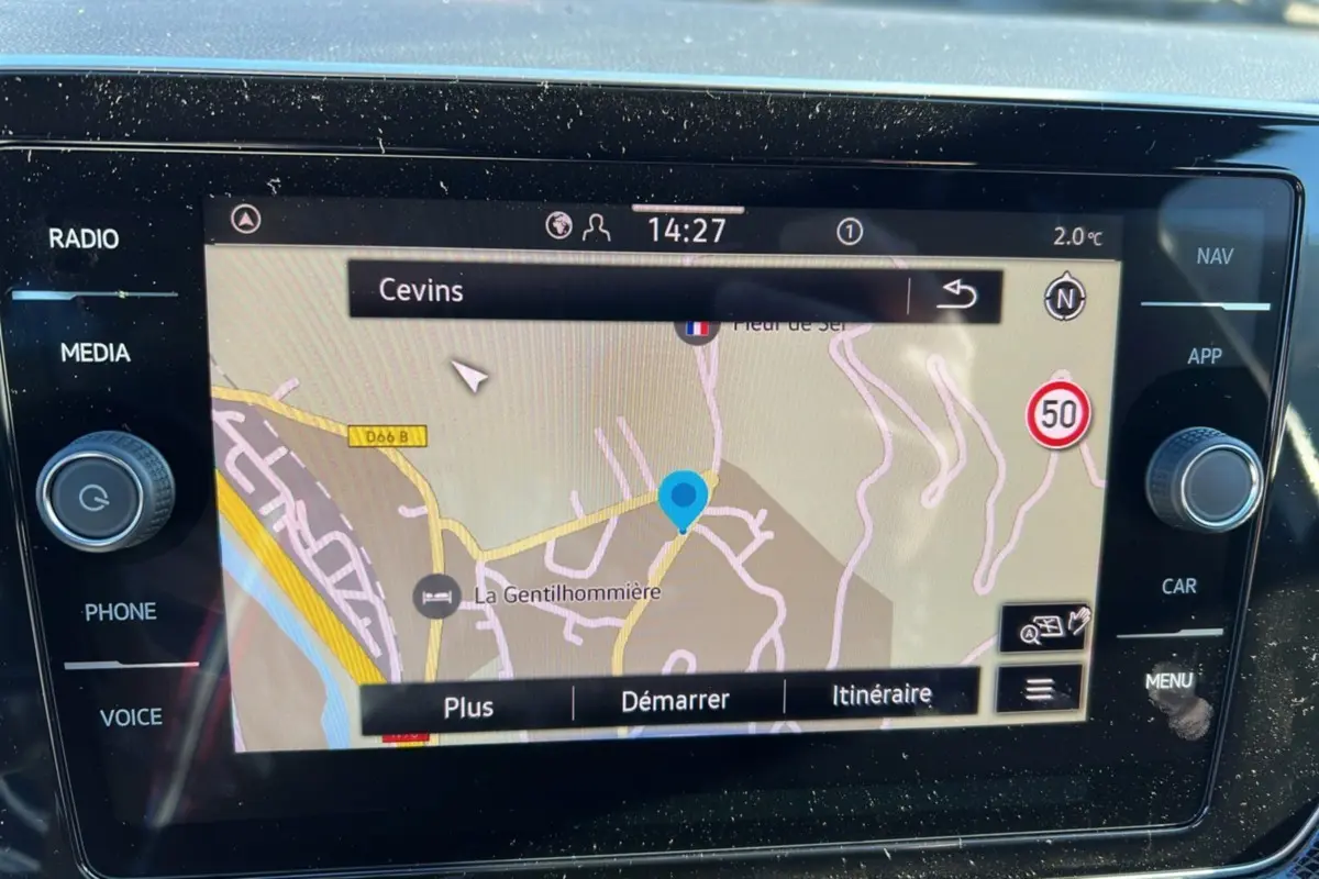 Écran tactile du système de navigation du Volkswagen T-Cross blanc, affichant une carte avec itinéraire et commandes latérales.