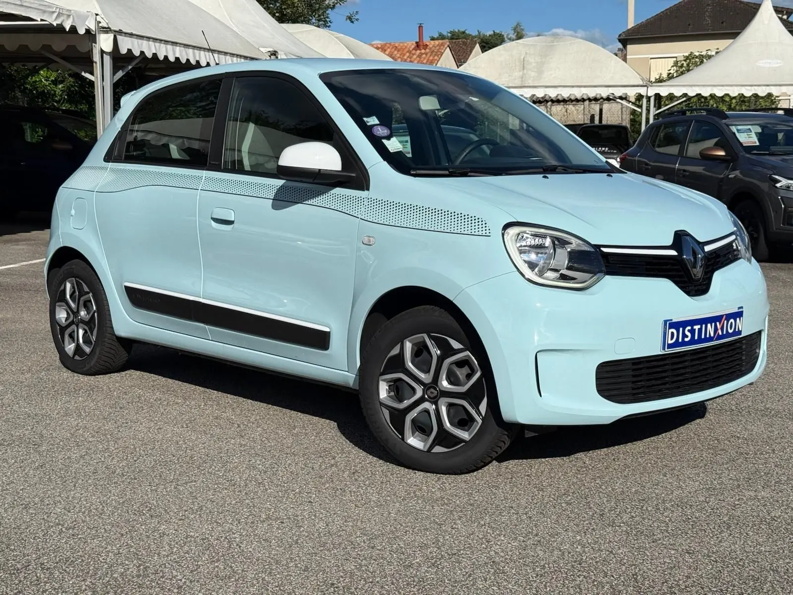 Renault Twingo III bleu dragée vue 3/4 avant droit, avec bandes décoratives noires et rétroviseurs blancs.