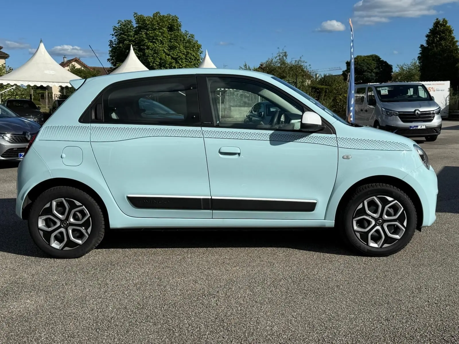 Profil droit de la Renault Twingo III bleu dragée 2021 avec jantes stylisées et bande décorative noire sur la carrosserie.
