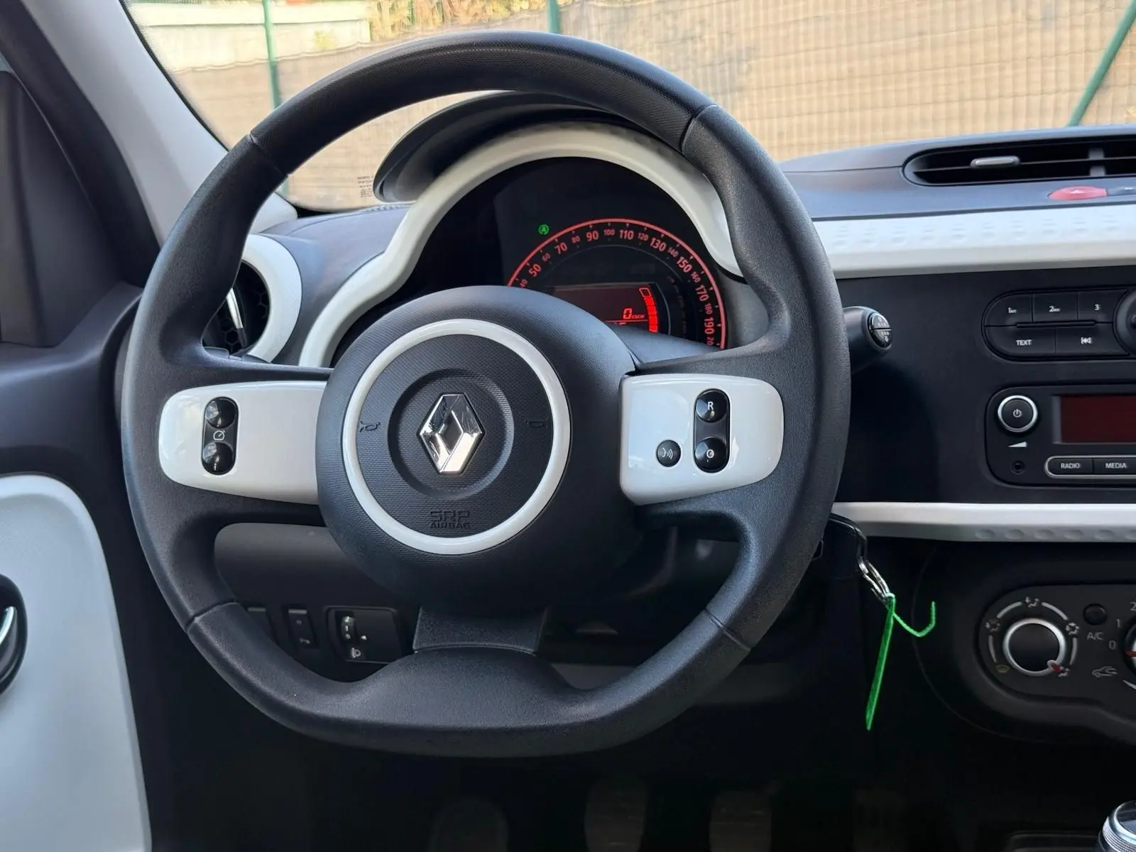 Vue rapprochée du volant noir et blanc de la Renault Twingo III 2021 avec tableau de bord et commandes visibles.