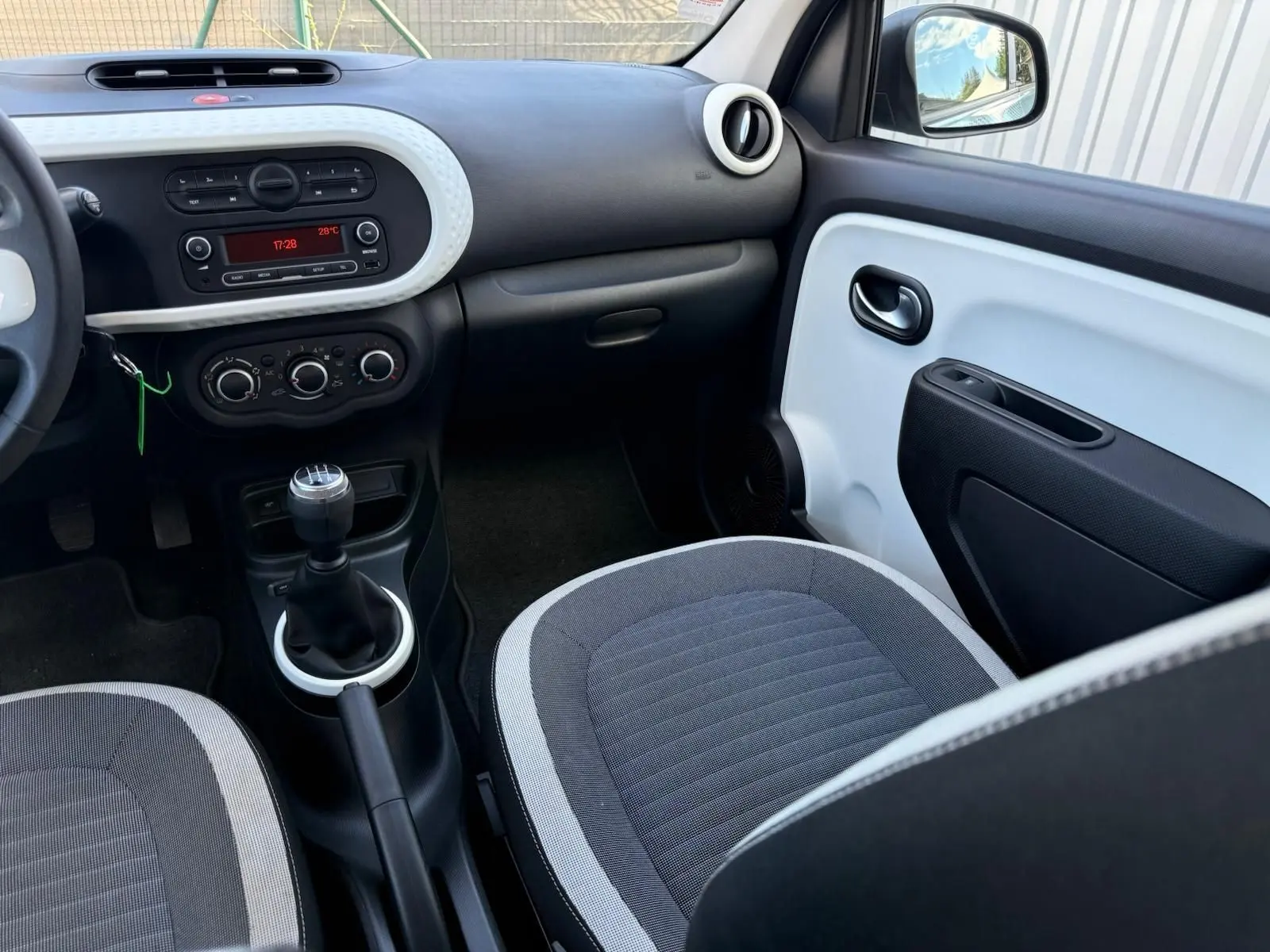 Intérieur avant droit de la Renault Twingo III 2021, tableau de bord noir et blanc avec levier de vitesse manuel.