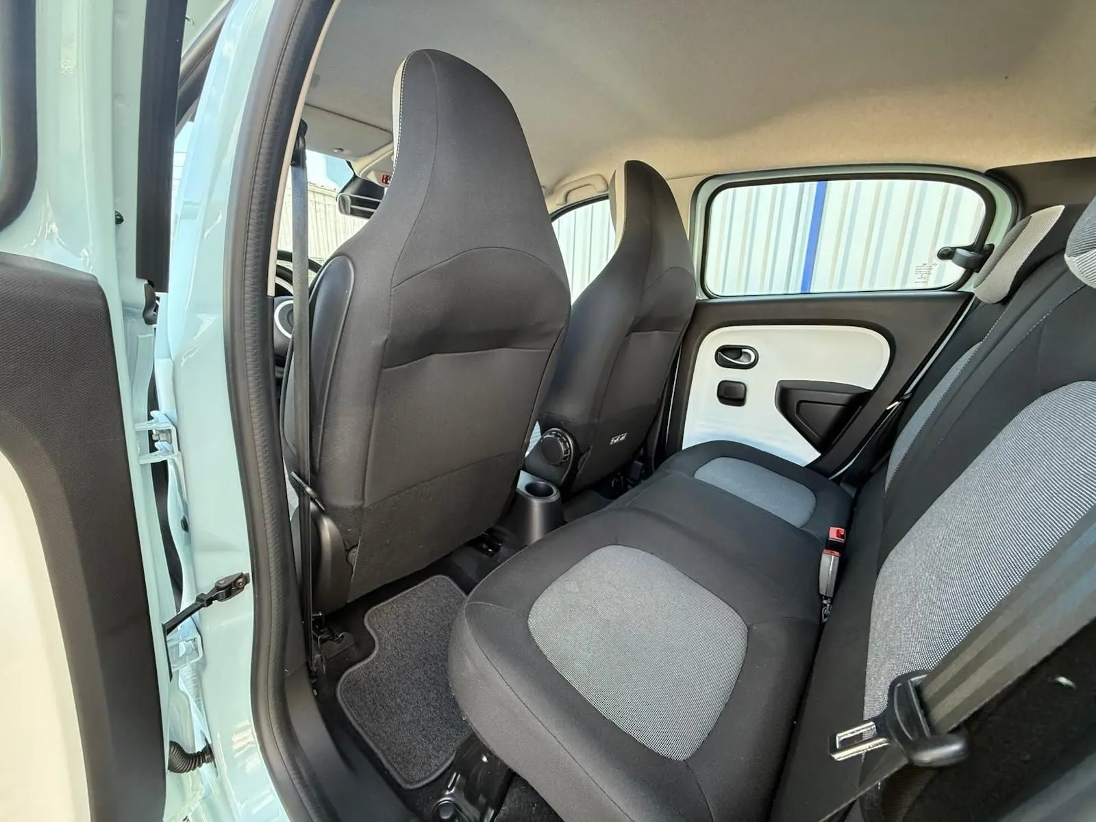 Vue intérieure arrière côté gauche d'une Renault Twingo III bleu dragée, sièges tissu bicolore gris et noir.