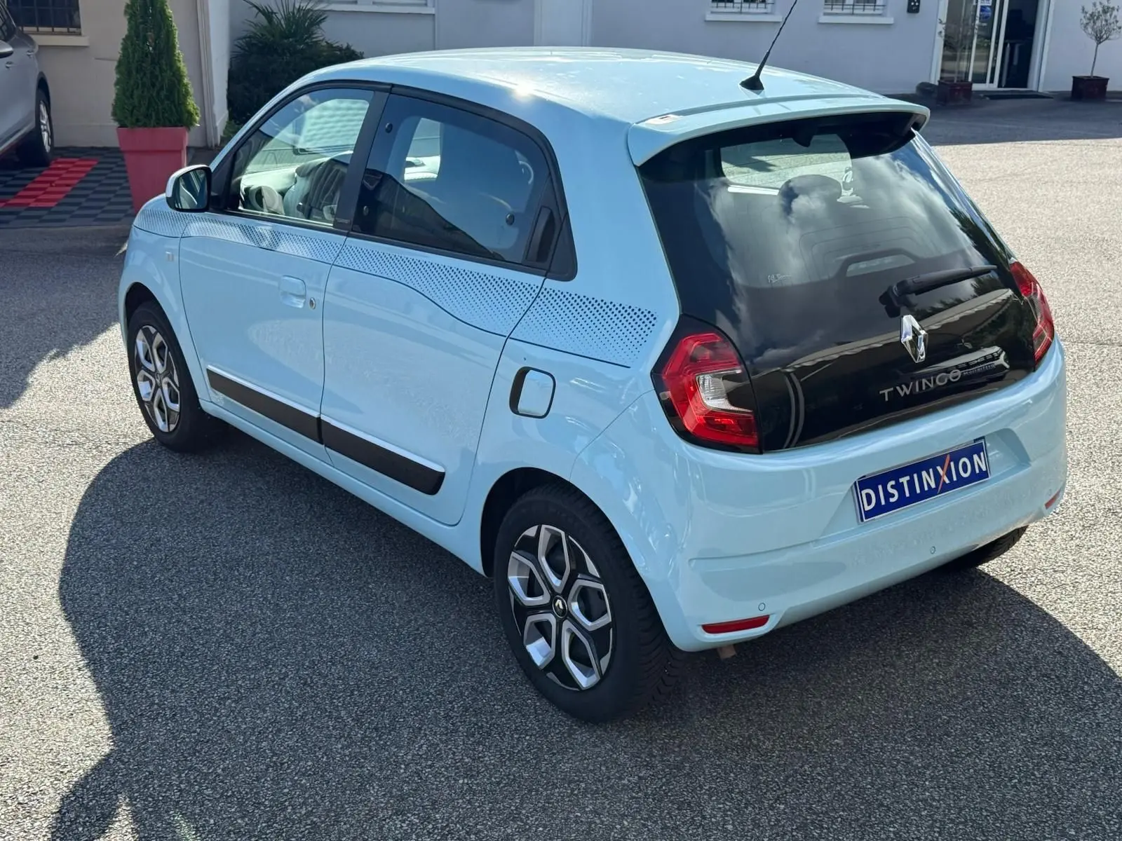 Vue 3/4 arrière droite d'une Renault Twingo III bleu dragée avec toit noir et jantes stylisées.