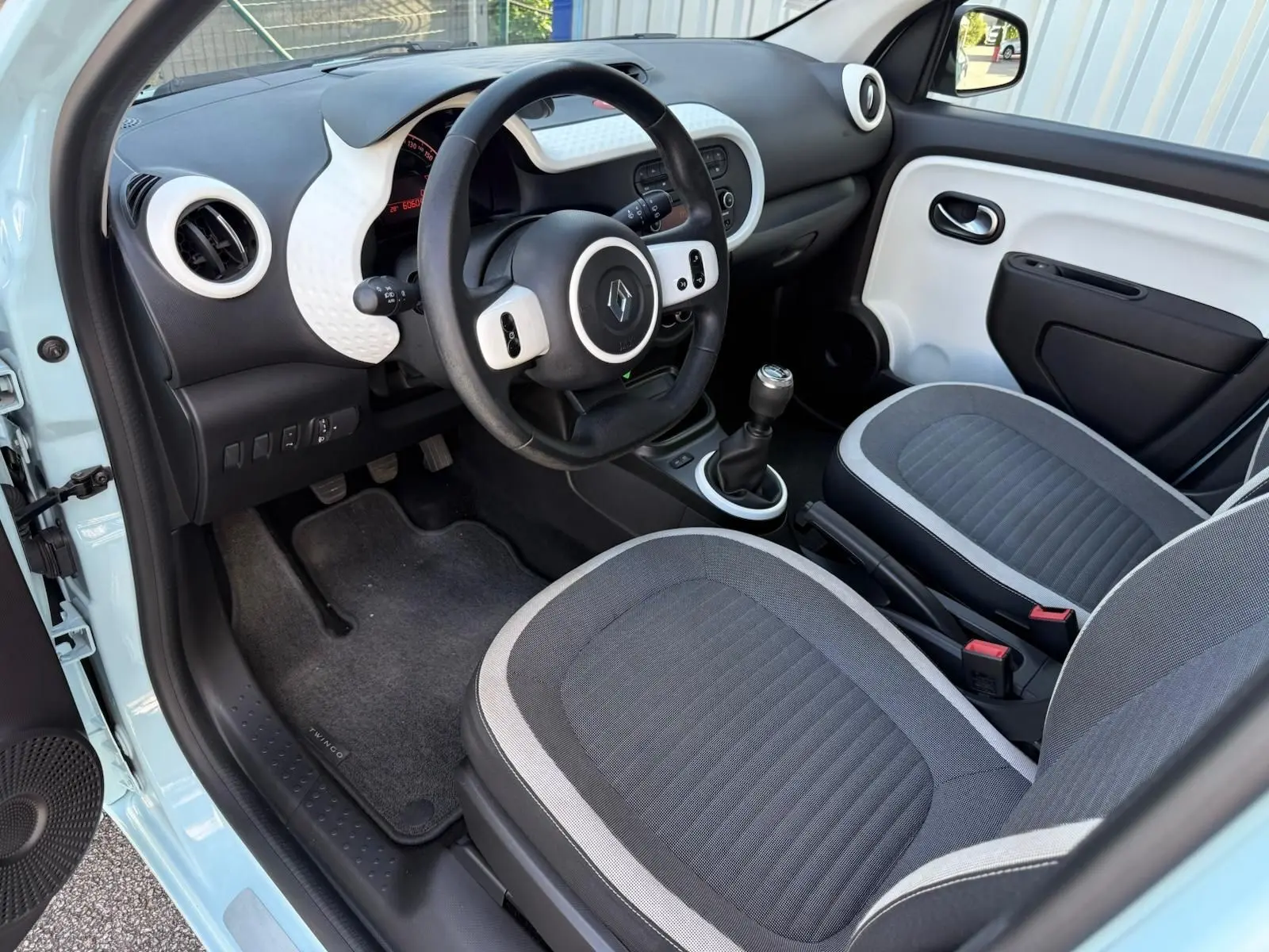 Vue intérieure côté conducteur de la Renault Twingo III bleu dragée, avec tableau de bord et sièges gris.