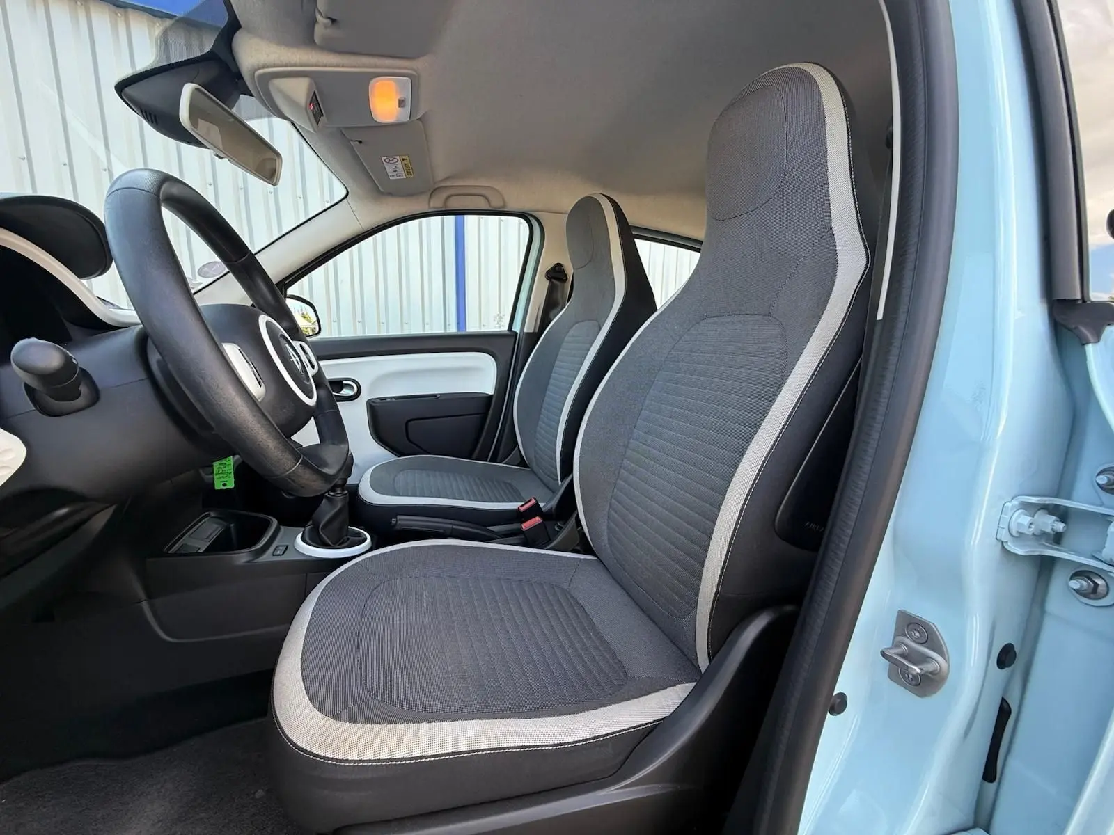 Intérieur de la Renault Twingo III bleu dragée, vue côté gauche sur les sièges avant gris avec contours clairs.