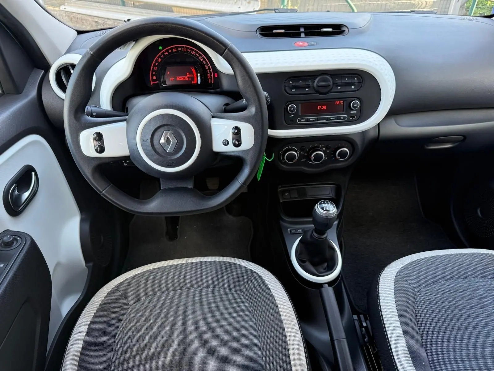 Vue intérieure avant de la Renault Twingo III 2021, volant rond noir et blanc, tableau de bord avec commandes et levier de vitesse manuel.