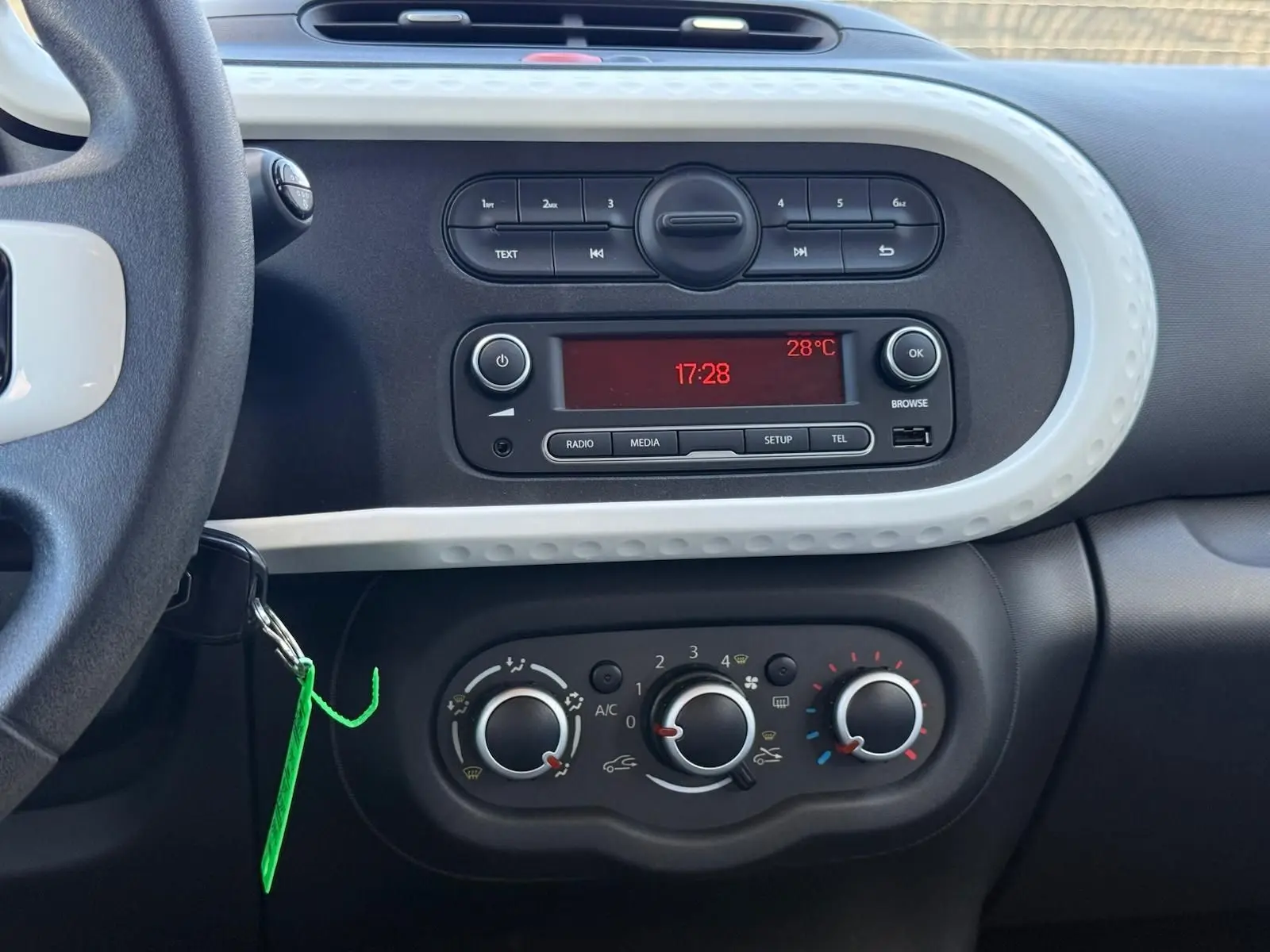 Vue rapprochée du tableau de bord de la Renault Twingo III bleu dragée, montrant la radio et les commandes de climatisation.