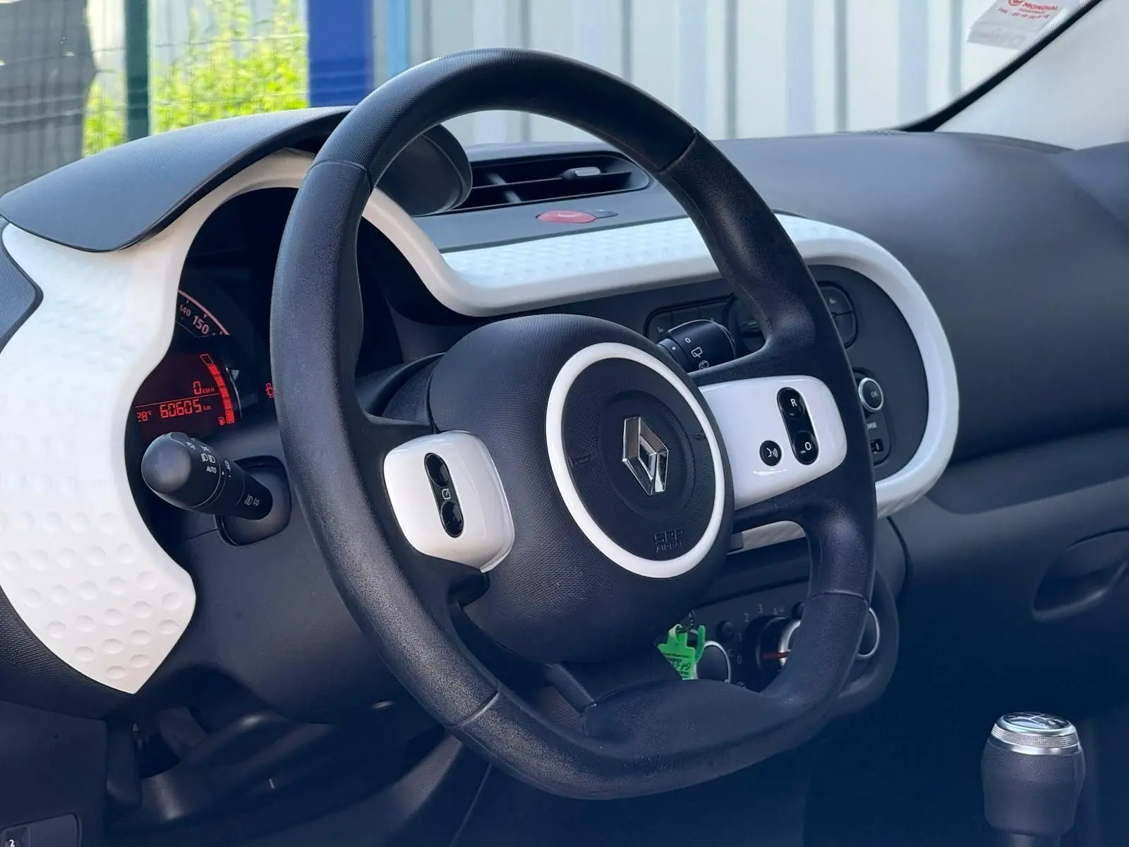 Intérieur de la Renault Twingo III 2021, vue sur le volant noir avec inserts blancs et tableau de bord digital rouge.