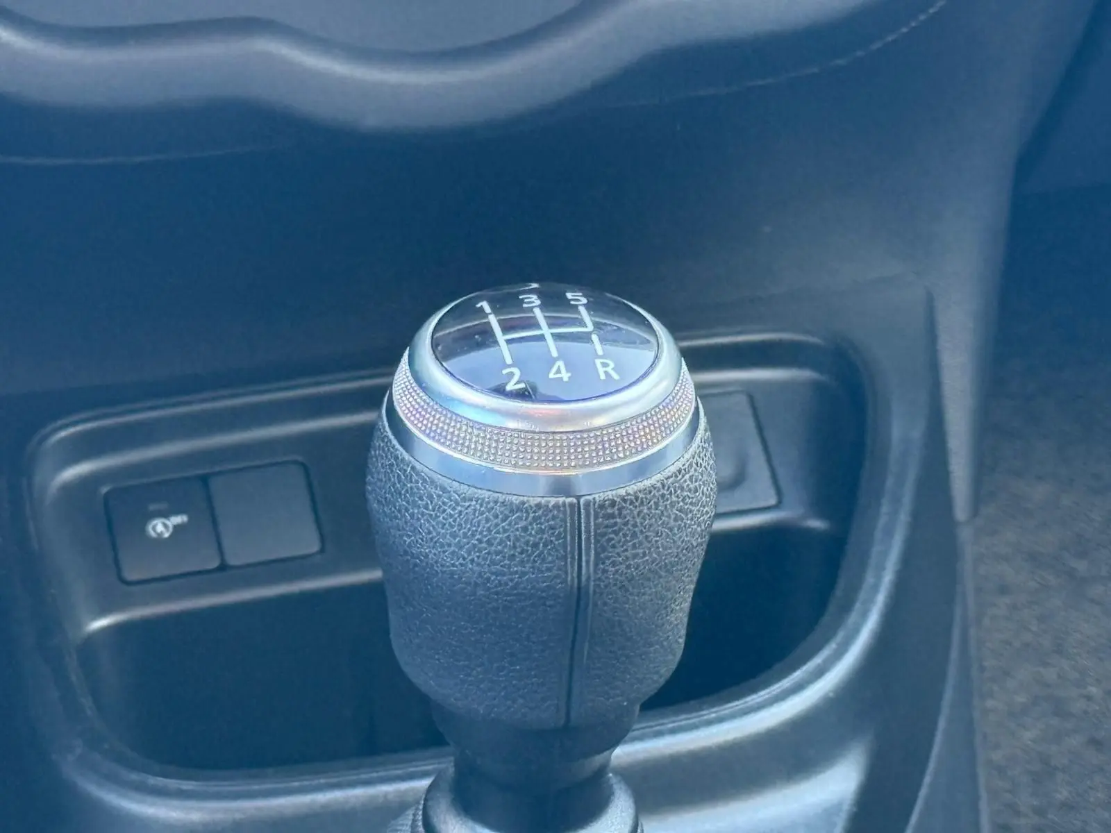 Le levier de vitesses manuel de la Renault Twingo III bleu dragée, vu en gros plan dans l'habitacle.