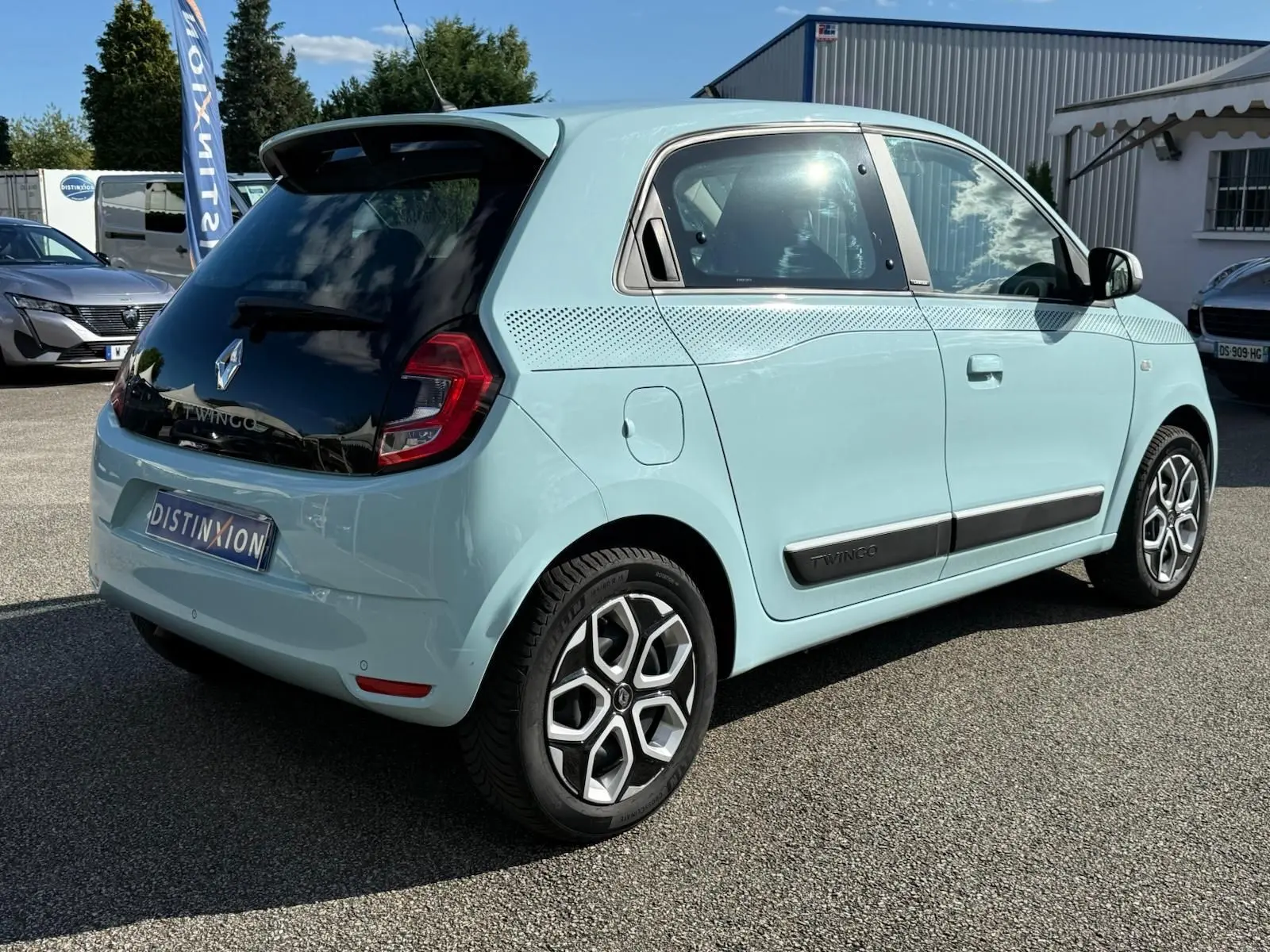 Renault Twingo III bleu dragée vue 3/4 arrière droit avec toit noir et jantes au design moderne.