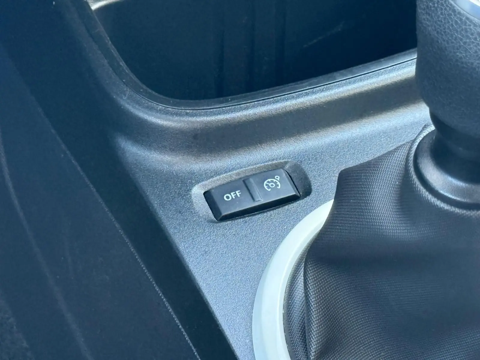 Gros plan sur le bouton de régulateur de vitesse désactivé à côté du levier de vitesses d'une Renault Twingo III bleu dragée.