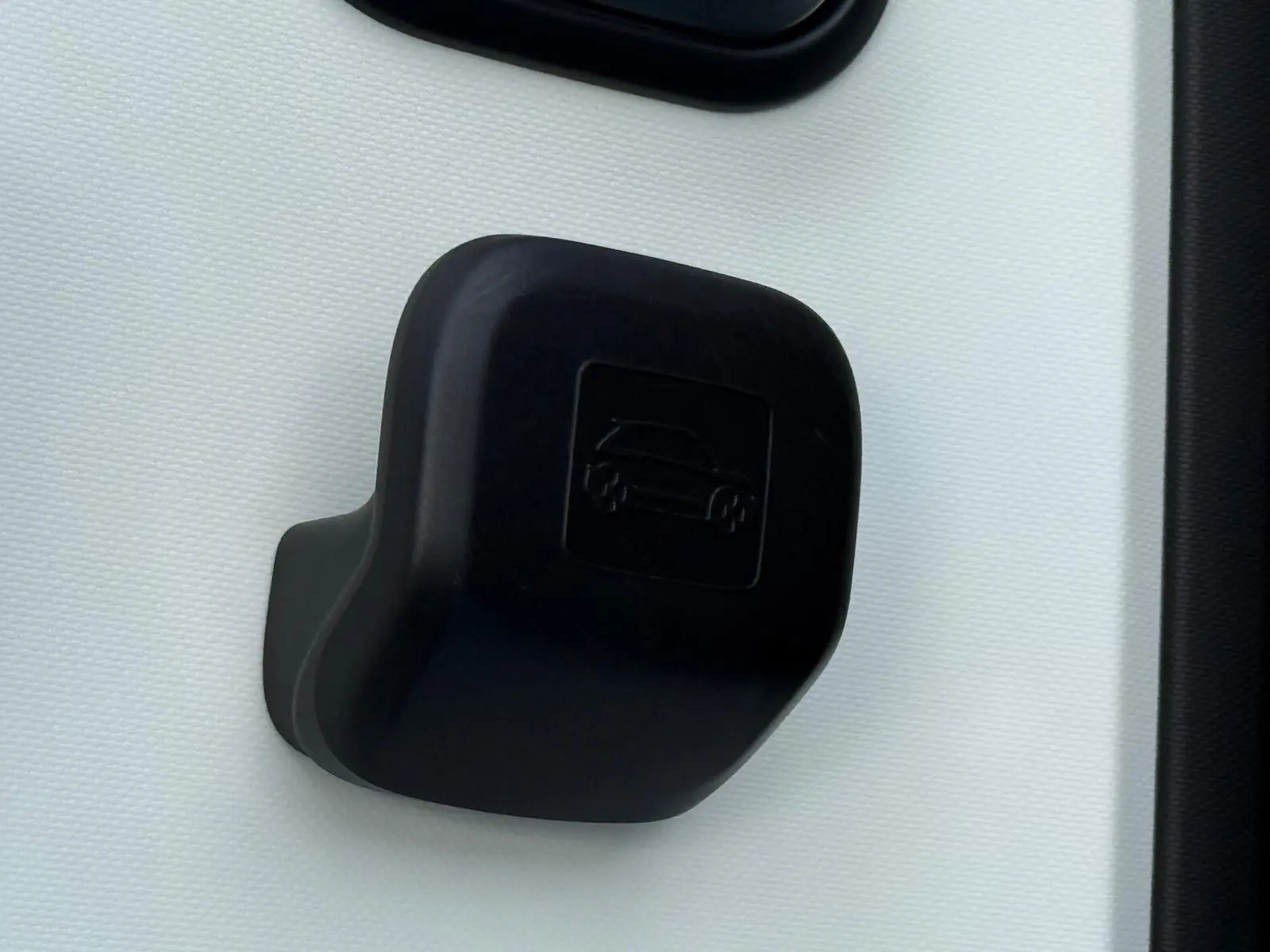 Gros plan sur la poignée intérieure de porte noire d'une Renault Twingo III bleu dragée, mettant en valeur le pictogramme voiture embossé.