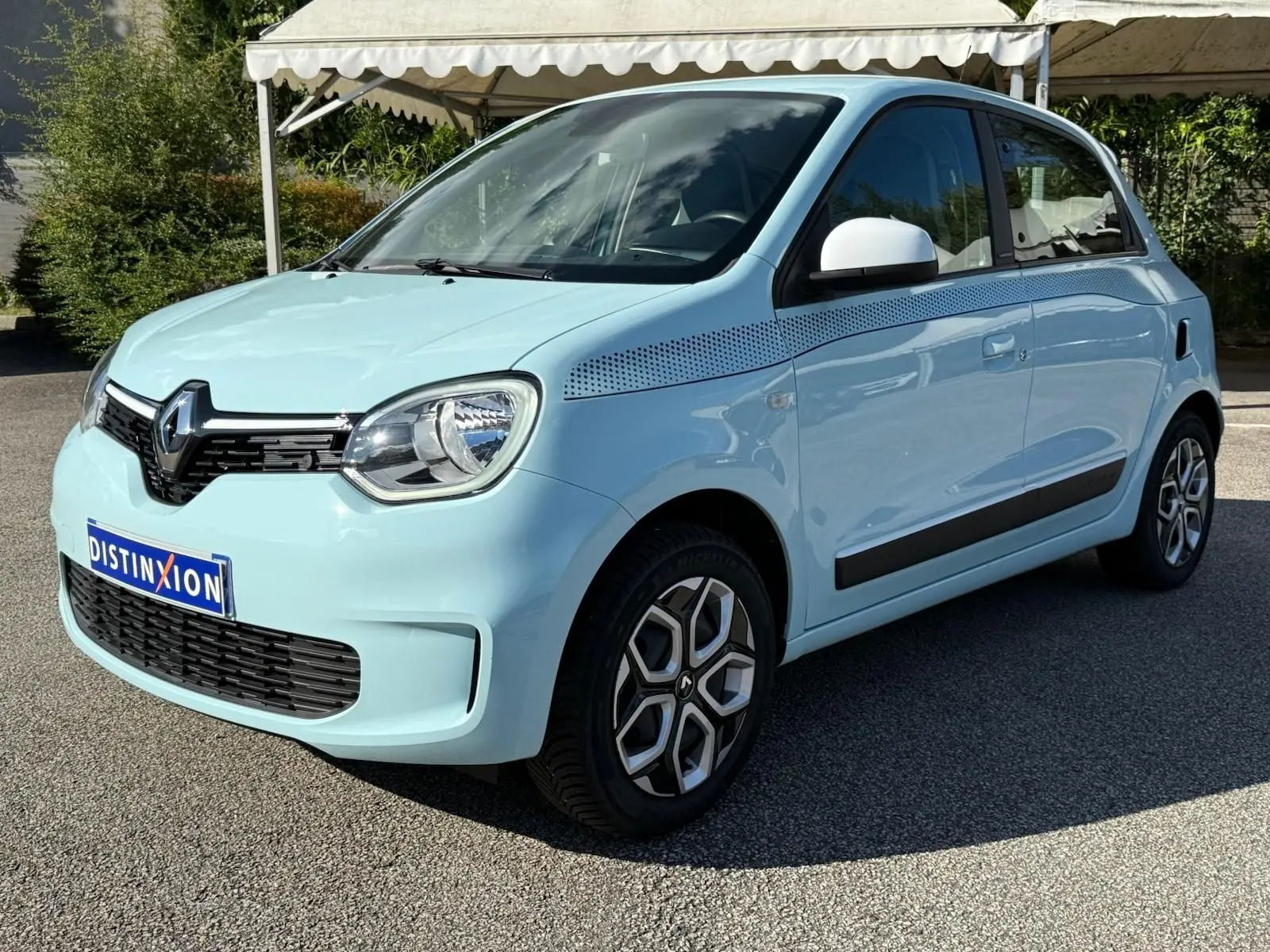 Renault Twingo III bleu dragée vue 3/4 avant droit avec jantes originales et détails noirs sur la carrosserie.