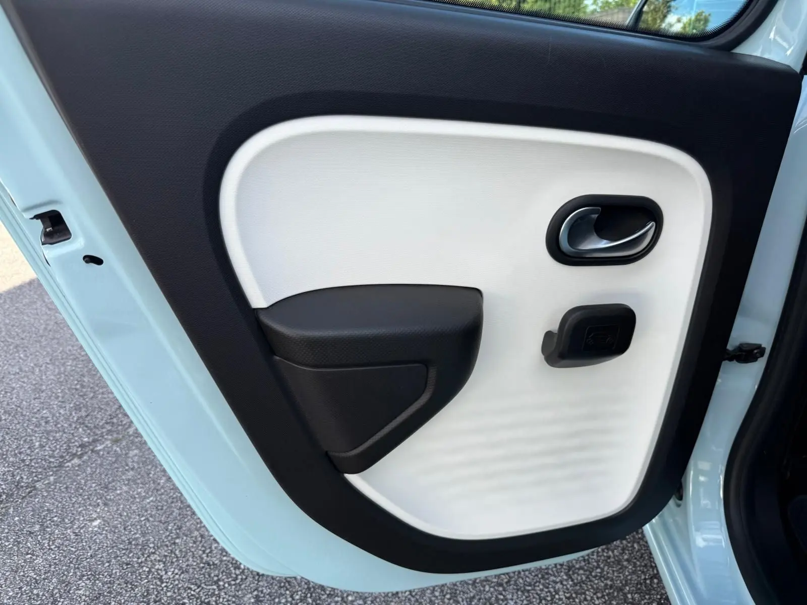 Détail de la porte arrière gauche bleu dragée de la Renault Twingo III 2021 avec poignée et accoudoir noir et blanc.