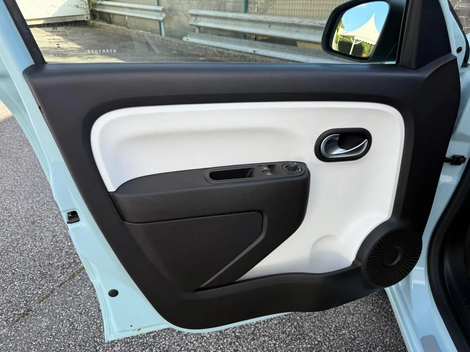 Vue intérieure de la porte côté gauche d'une Renault Twingo III bleu dragée avec panneau bicolore noir et blanc.