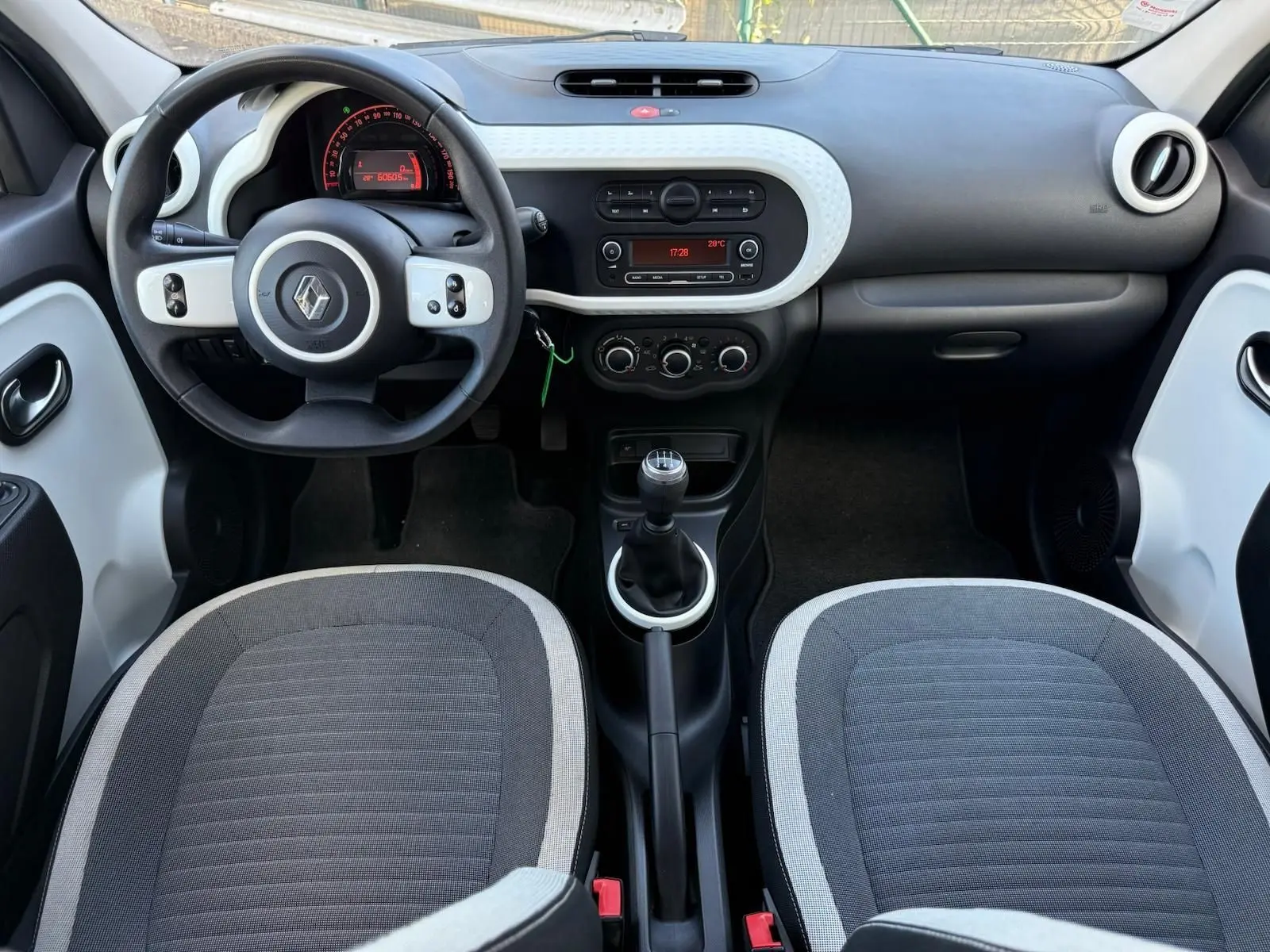 Vue intérieure avant de la Renault Twingo III 2021 avec tableau de bord noir et blanc et boîte manuelle.