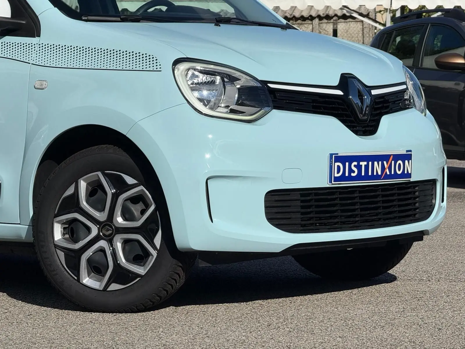 Vue 3/4 avant gauche d'une Renault Twingo III bleu dragée avec jantes au design géométrique et calandre noire.