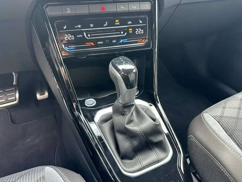 Gros plan sur la console centrale du Volkswagen T-ROC 2025 avec levier de boîte auto et commandes climatisation digitales.