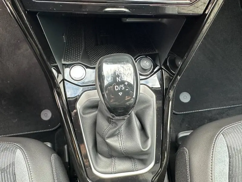 Le levier de vitesse automatique noir brillant du Volkswagen T-Roc 2025, vu de dessus, entouré de garnitures noires.