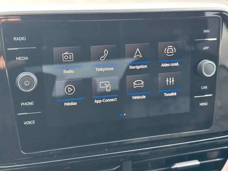 Écran tactile central du Volkswagen T-Roc 2025 affichant les options radio, téléphone, navigation et aides à la conduite.