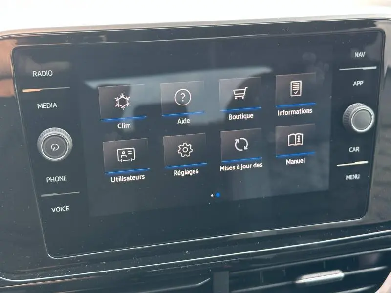 Écran tactile central du Volkswagen T-Roc 2025 affichant les menus radio, climatisation et réglages dans un intérieur noir.
