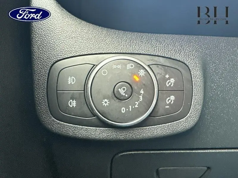 Gros plan sur le bouton de réglage des phares et éclairages intérieurs du tableau de bord d'une Ford Fiesta gris lunaire.