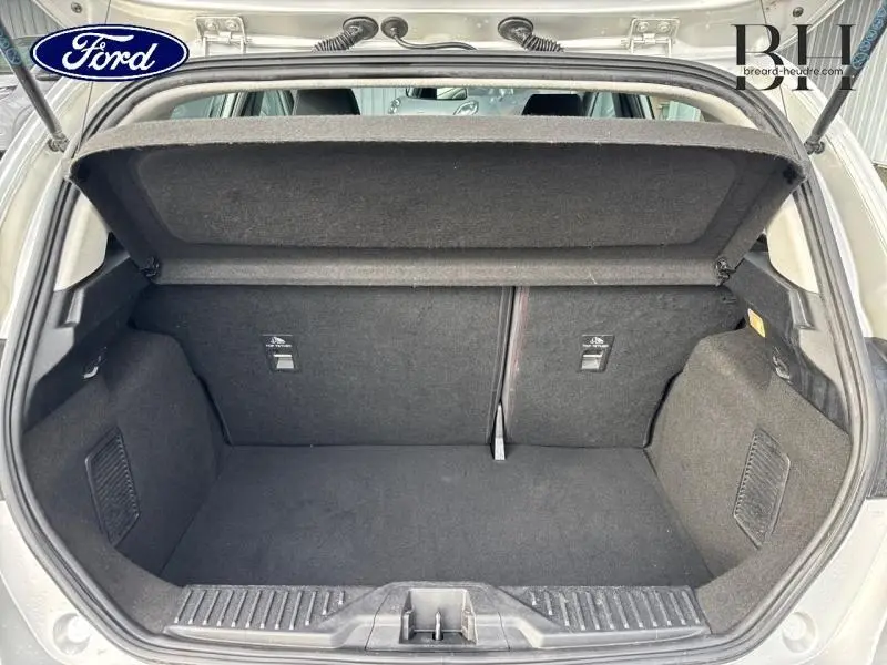 Vue arrière du coffre ouvert d'une Ford Fiesta gris lunaire, montrant l'espace de rangement et la banquette arrière.