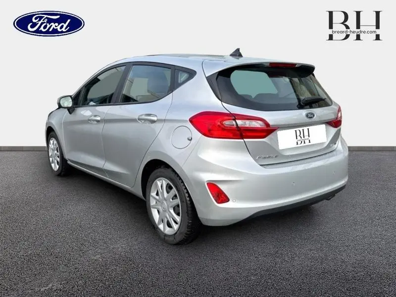 Vue 3/4 arrière droite d'une Ford Fiesta gris lunaire avec becquet et feux arrière rouges distinctifs.