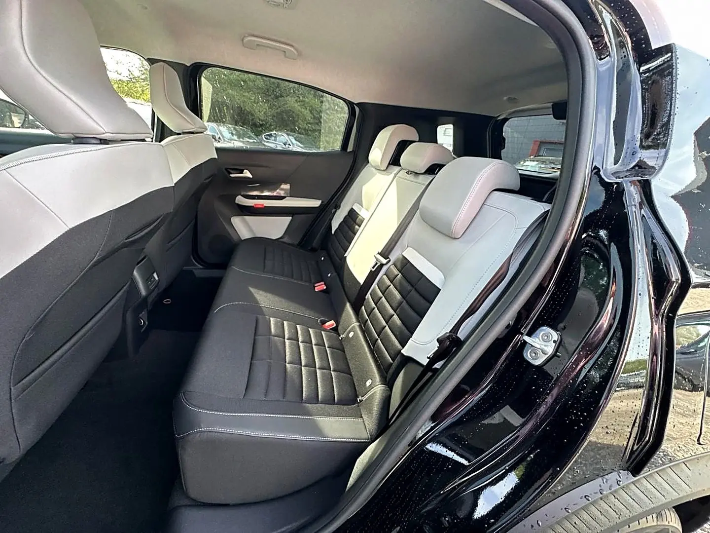 Vue intérieure arrière côté droit du Citroën C3 Aircross noir 2026 avec sièges bicolores noir et clair.