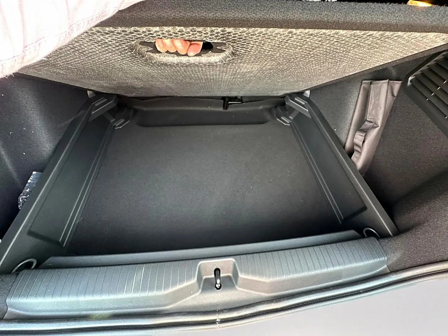 Vue plongeante sur le coffre noir vide du Citroën C3 Aircross 2026, montrant le plancher de coffre mobile et la poignée intégrée.