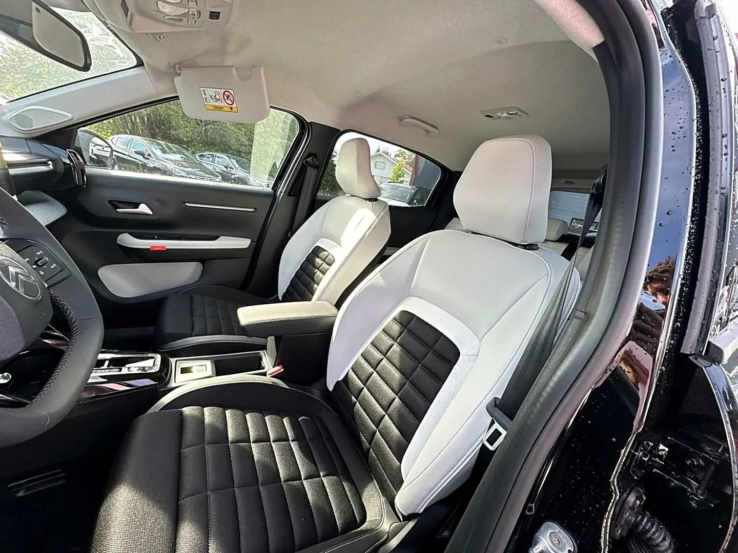 Vue intérieure côté conducteur de la Citroën C3 Aircross noire 2026, sièges bicolores noir et blanc avec accoudoir central.