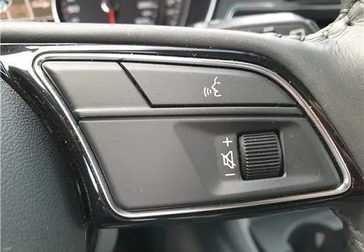 Gros plan sur les commandes de volume et d'assistance vocale sur le volant d'une Audi A4 Avant Business gris Terra 2020.