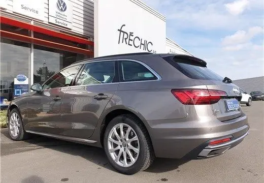 Audi A4 Avant Business gris Terra vue 3/4 arrière droit, garée devant un bâtiment de service Volkswagen.