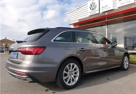 Audi A4 Avant Business gris Terra vue 3/4 arrière droit, stationnée devant un service Volkswagen et Audi.