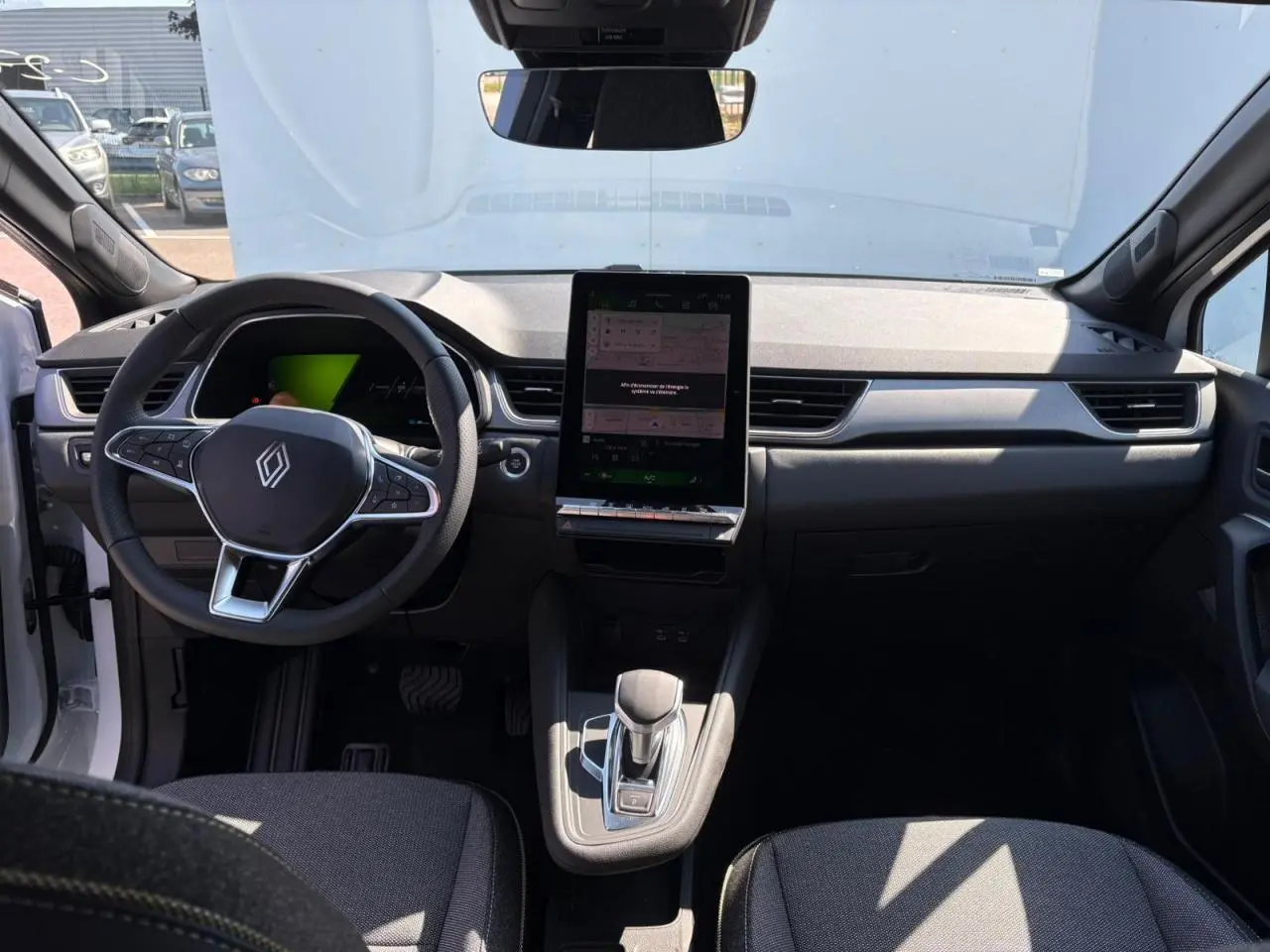 Intérieur avant du Renault Symbioz blanc nacré 2025 avec tableau de bord numérique et écran tactile vertical central.