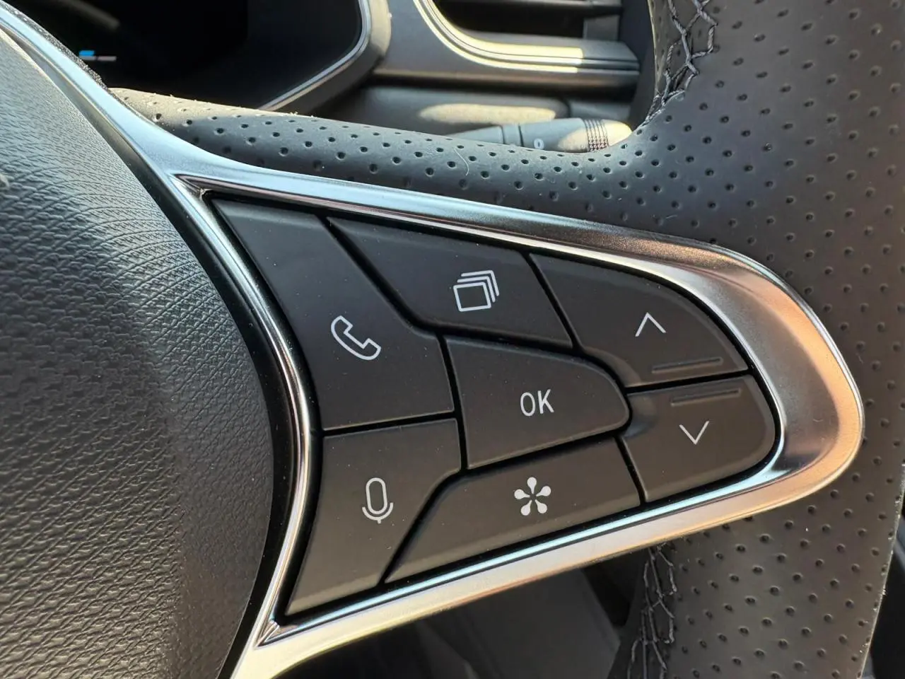 Gros plan sur les commandes multifonctions noires du volant perforé de la Renault Symbioz blanc nacré 2025.