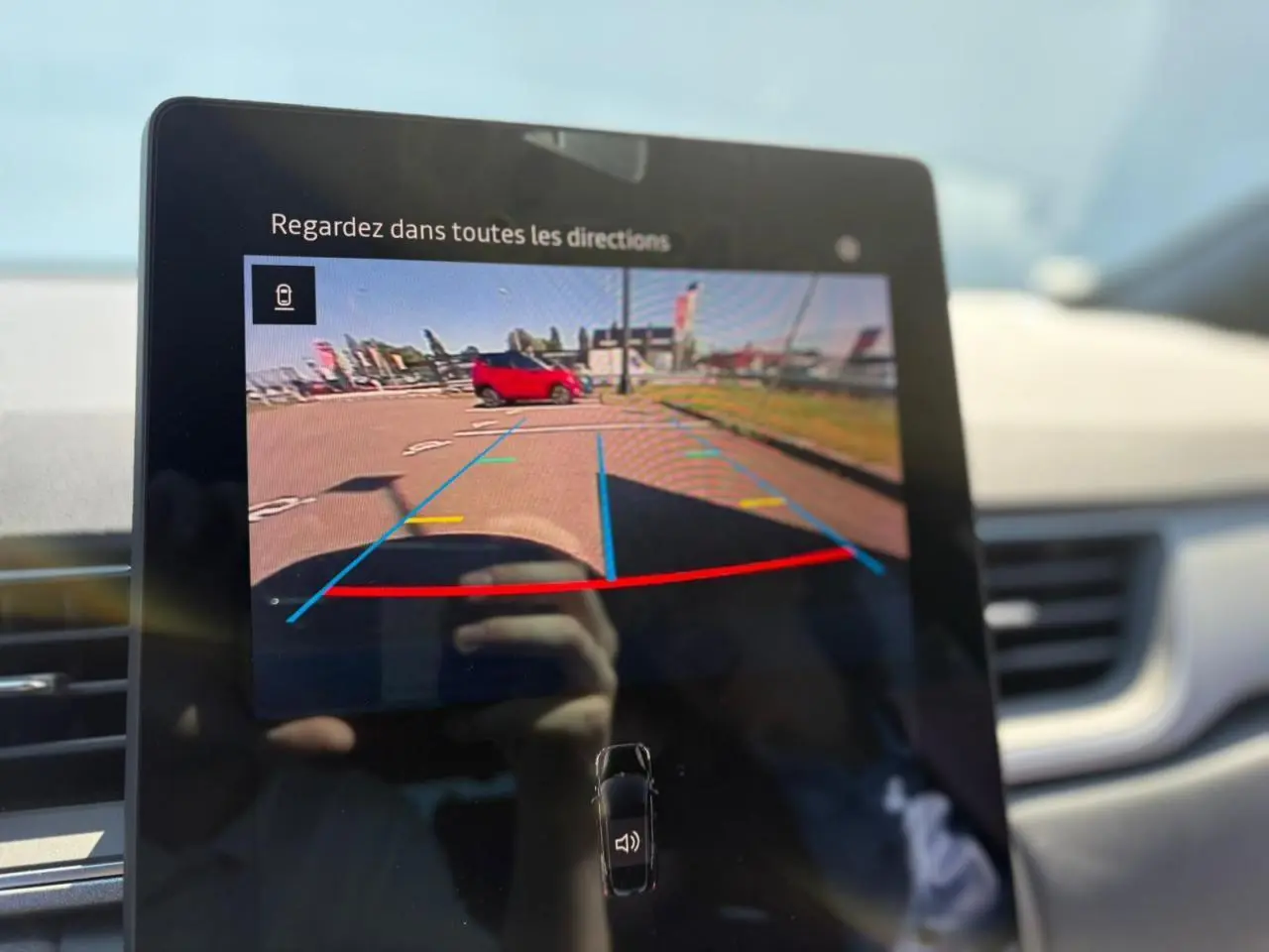 Écran de caméra de recul dans Renault Symbioz blanc nacré, vue intérieure avec indications de stationnement colorées.