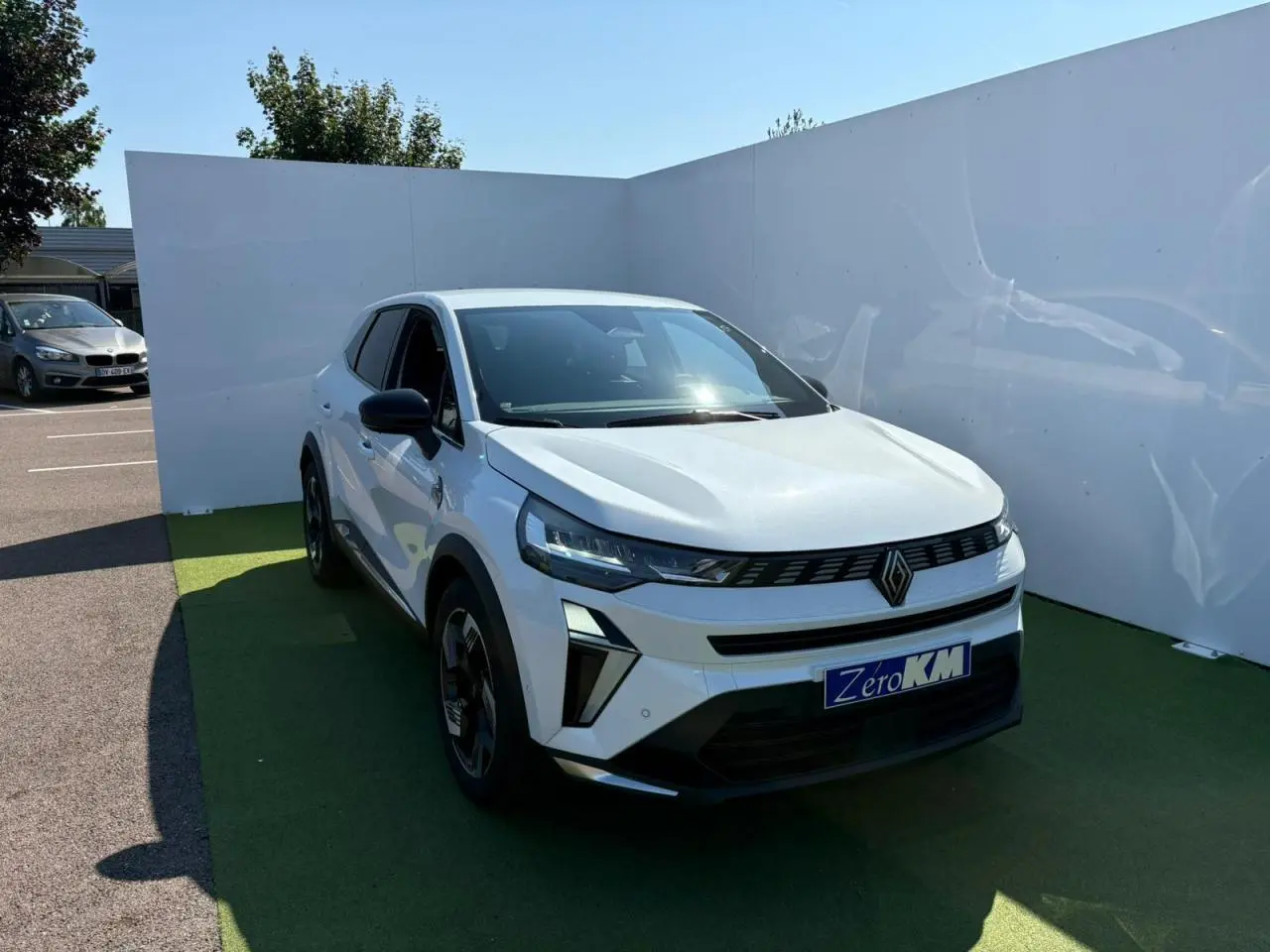 Renault Symbioz blanc nacré vu de 3/4 avant droit, calandre noire avec logo Renault centré et jantes 18 pouces noires.