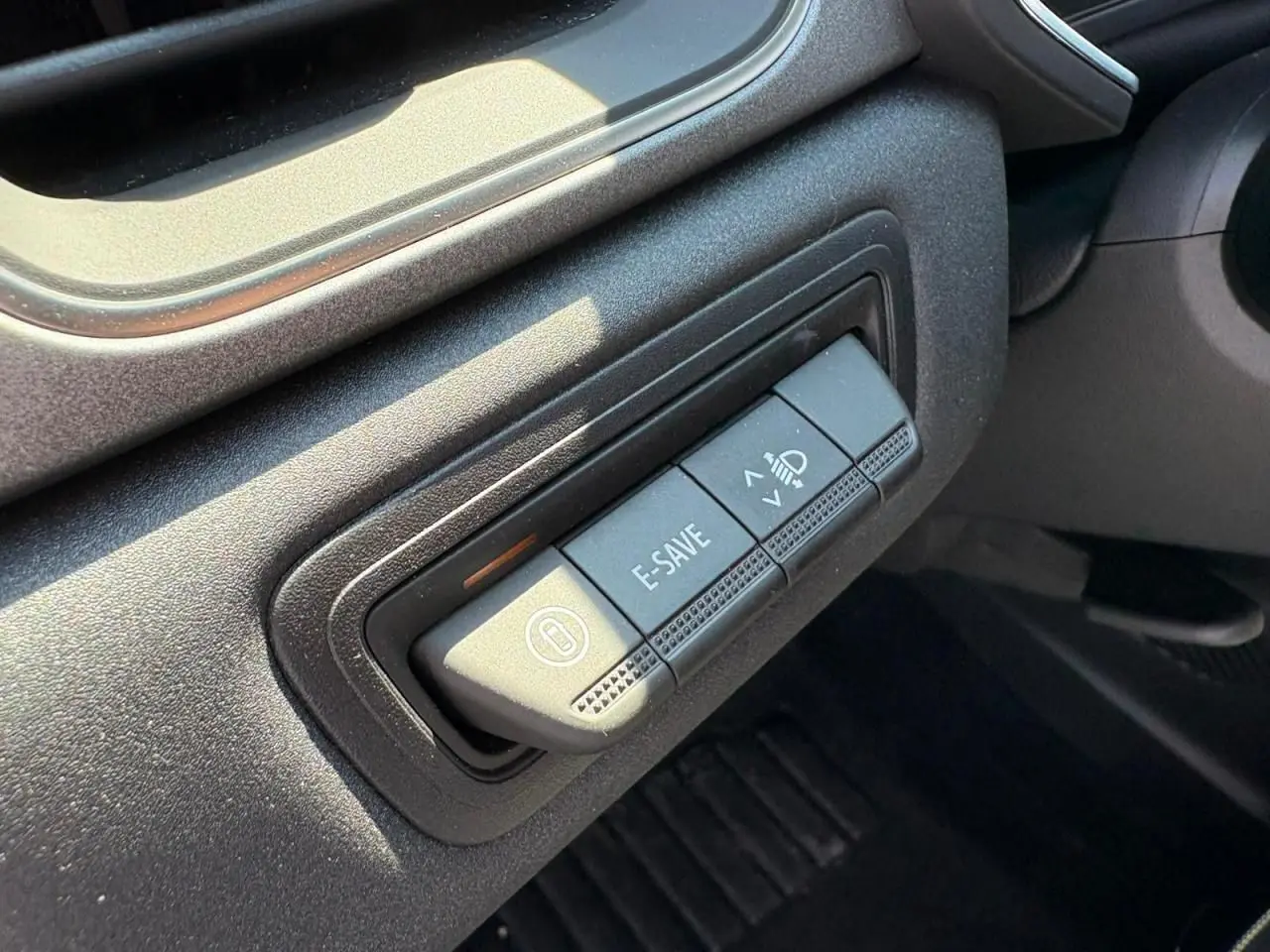 Gros plan sur les boutons de commande E-SAVE et réglage des phares dans l'habitacle noir du Renault Symbioz blanc nacré 2025.