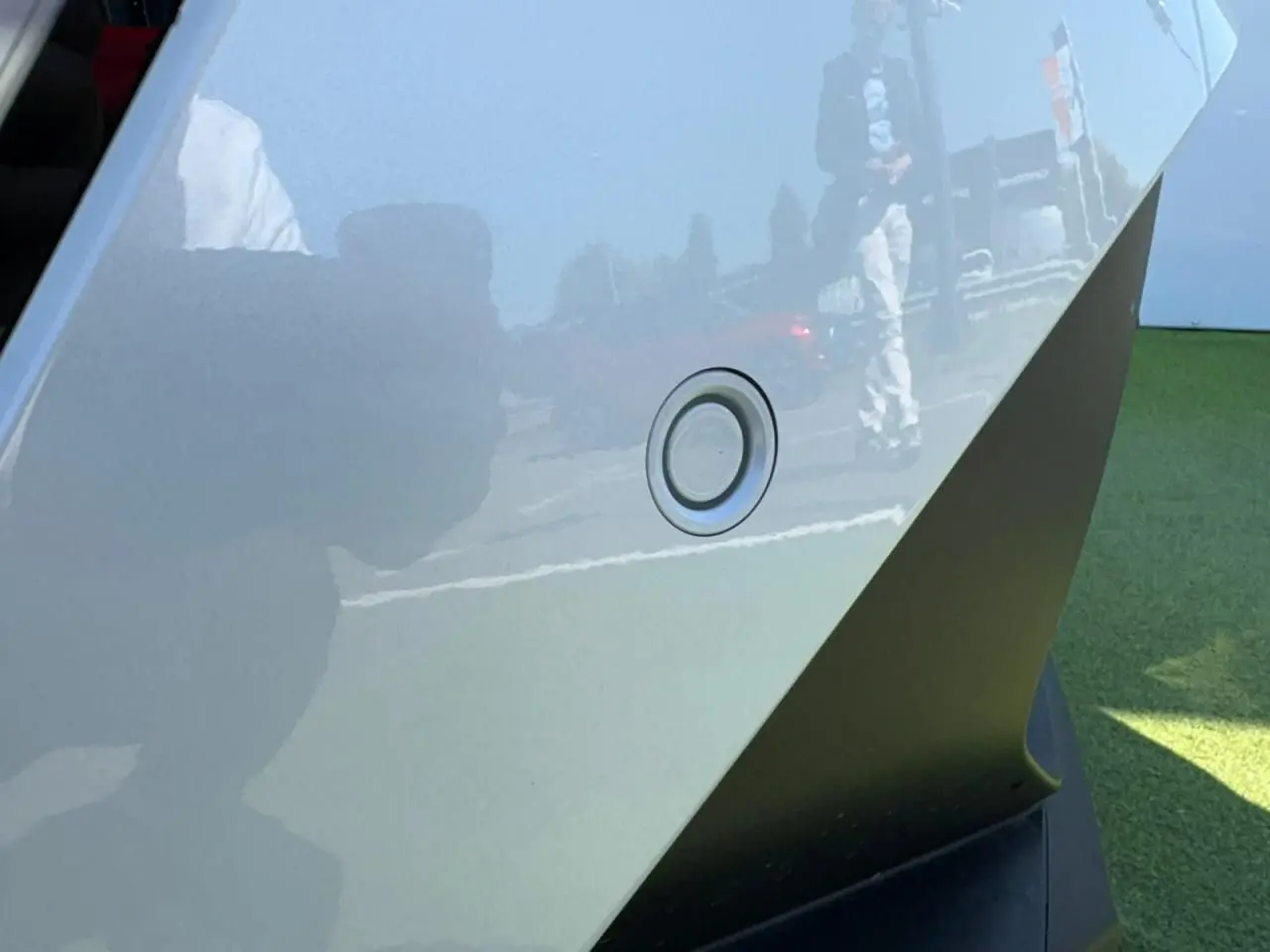 Gros plan sur un capteur de stationnement arrière du Renault Symbioz blanc nacré, reflétant l'environnement extérieur.