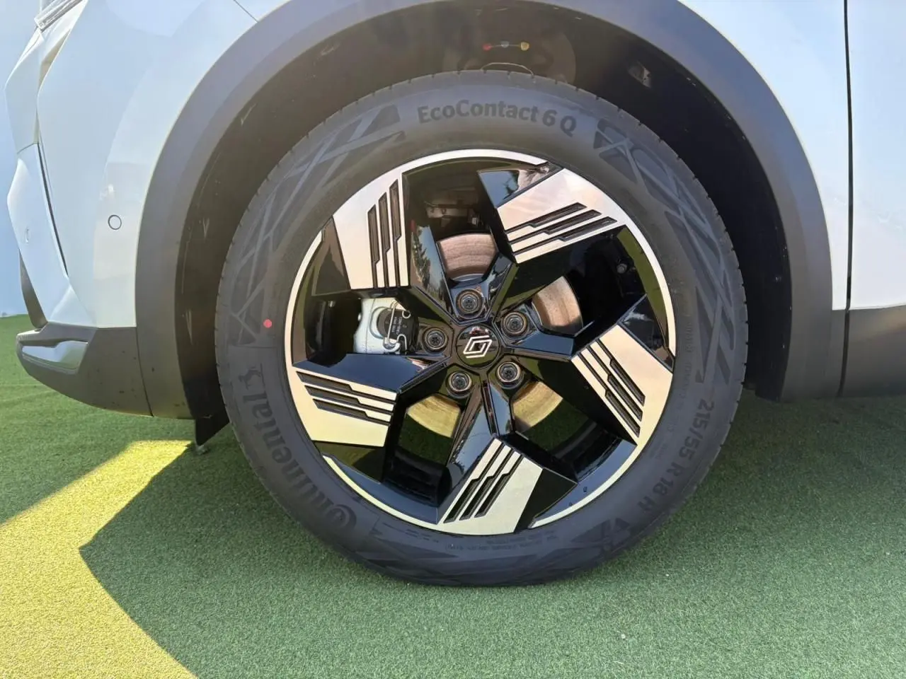 Gros plan sur la jante 18 pouces noire et argentée du côté droit du Renault Symbioz blanc nacré, avec pneu Continental.