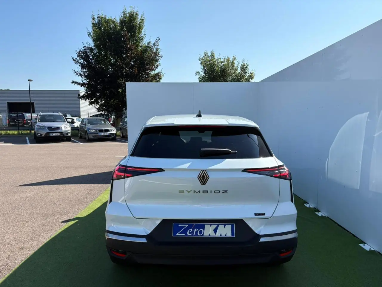 Vue arrière d'une Renault SYMBIOZ blanc nacré stationnée, avec feux arrière LED et logo central visible.