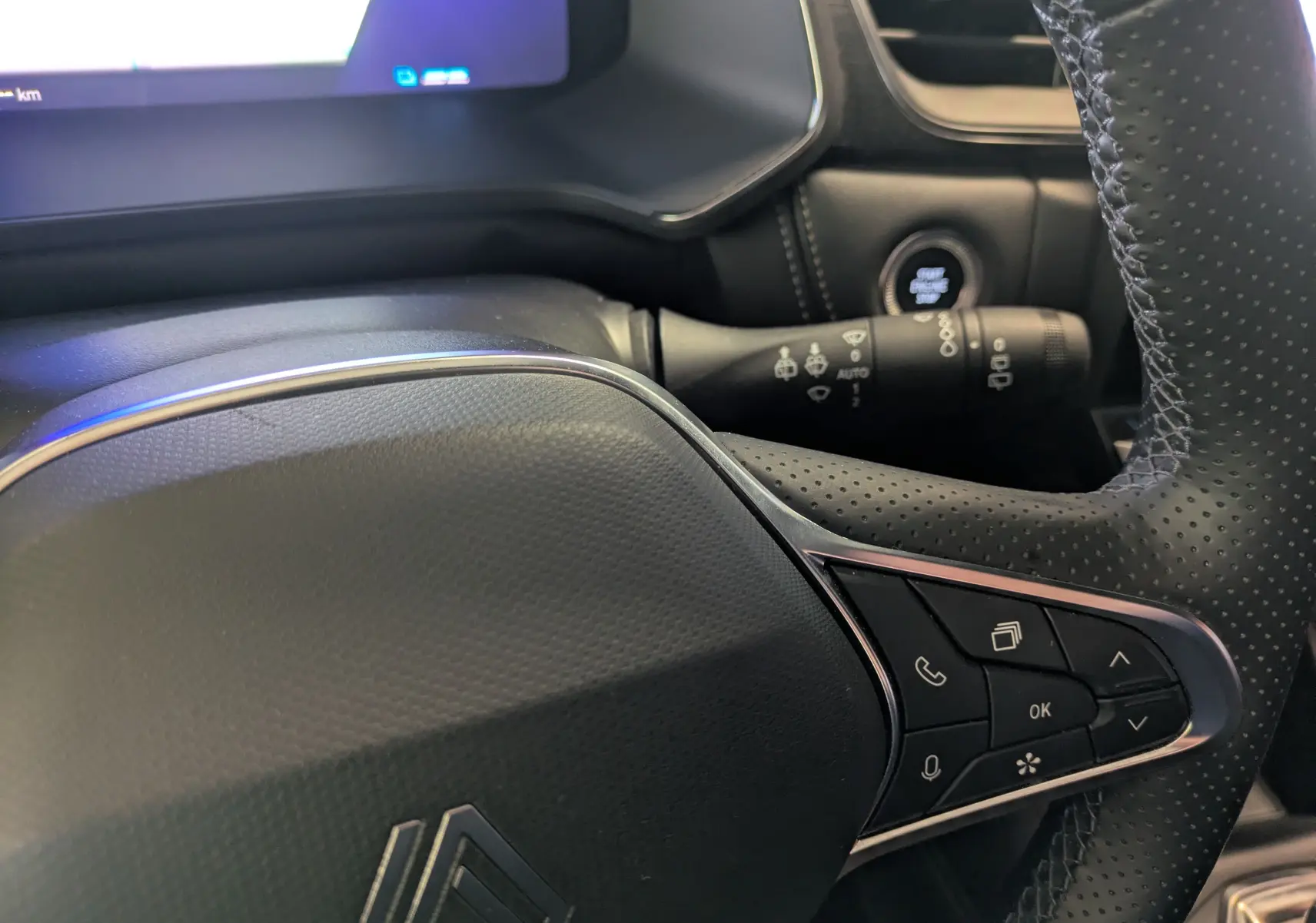 Gros plan sur le volant noir perforé côté droit du Renault Symbioz gris Cassiopée, avec commandes multifonctions et tableau de bord digital.