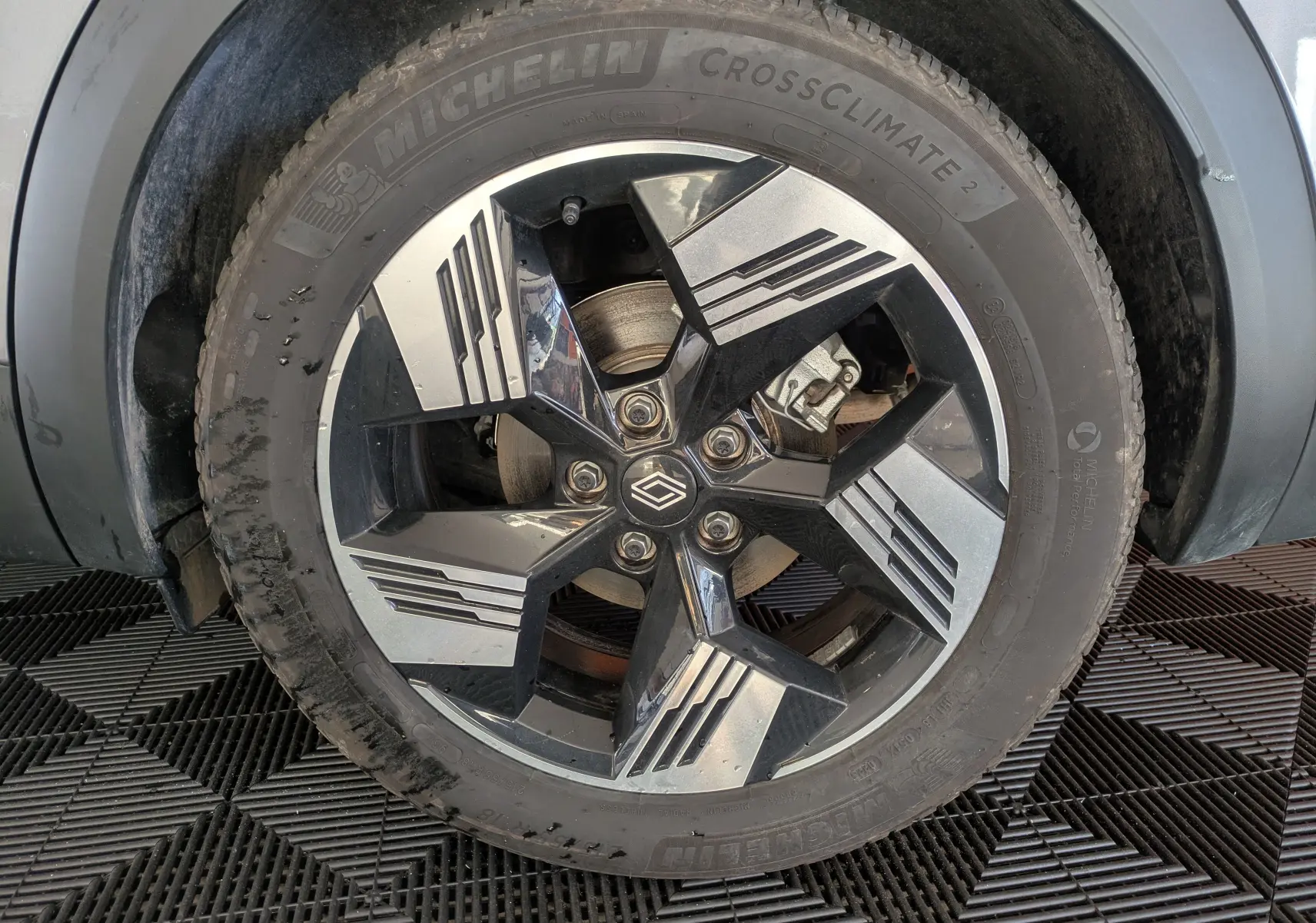 Gros plan sur la roue avant gauche du Renault Symbioz gris Cassiopée, jante alliage bicolore au design géométrique.