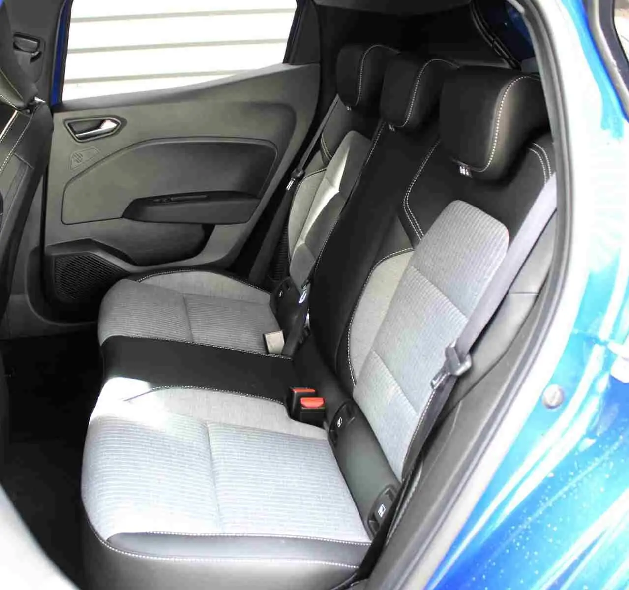 Vue intérieure côté conducteur de la Renault Clio 2025 bleu Iron Metal, sièges tissu gris noir avec surpiqûres contrastées.
