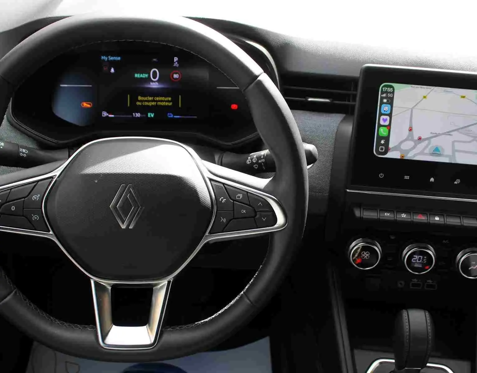Vue rapprochée du volant et du tableau de bord numérique de la Renault Clio hybride, avec écran tactile et commandes intégrées.