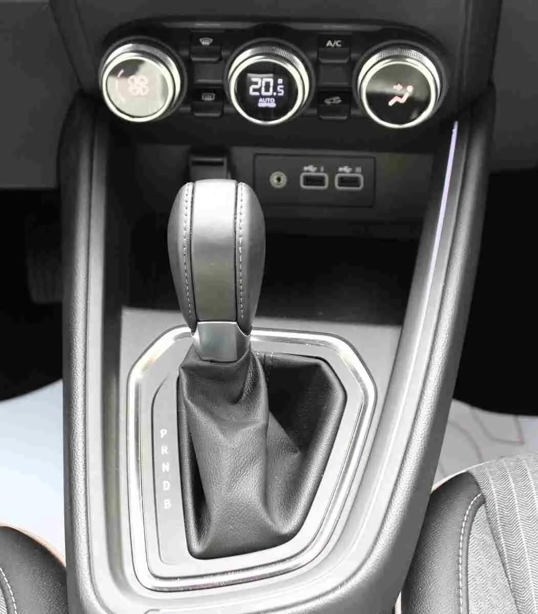 Gros plan sur la console centrale de la Renault Clio hybride 2025, montrant le levier de vitesse automatique et les commandes de climatisation.