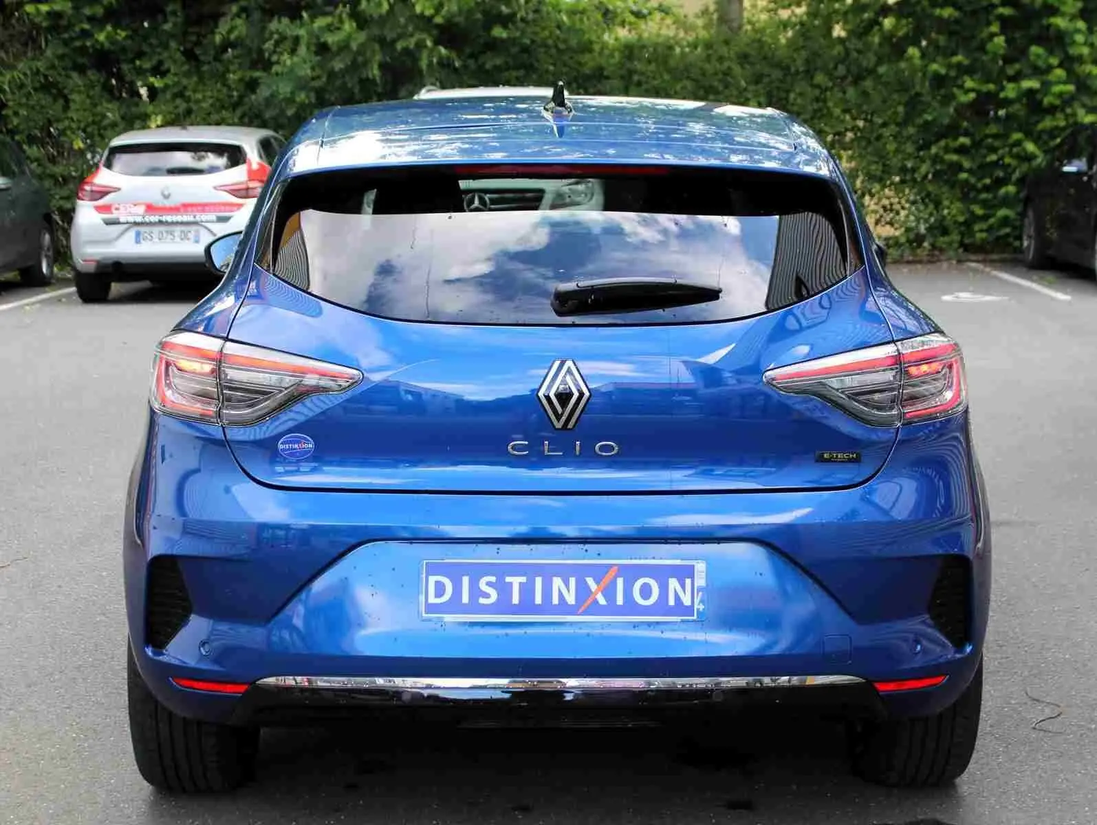 Profil droit de la Renault Clio 2025 bleu Iron Metal avec jantes alliage et vitres teintées, garée devant un bâtiment.